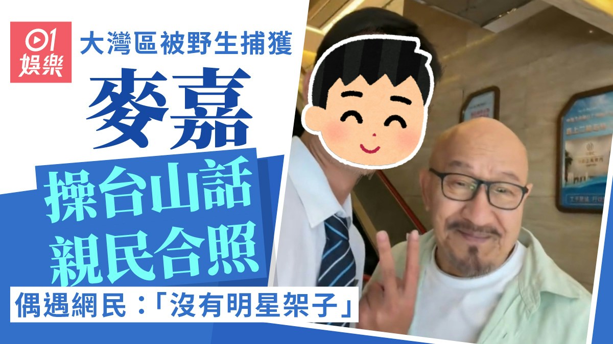 香港01の記事画像。眼鏡をかけた麦嘉がファンと並び、ピースサインをしている。