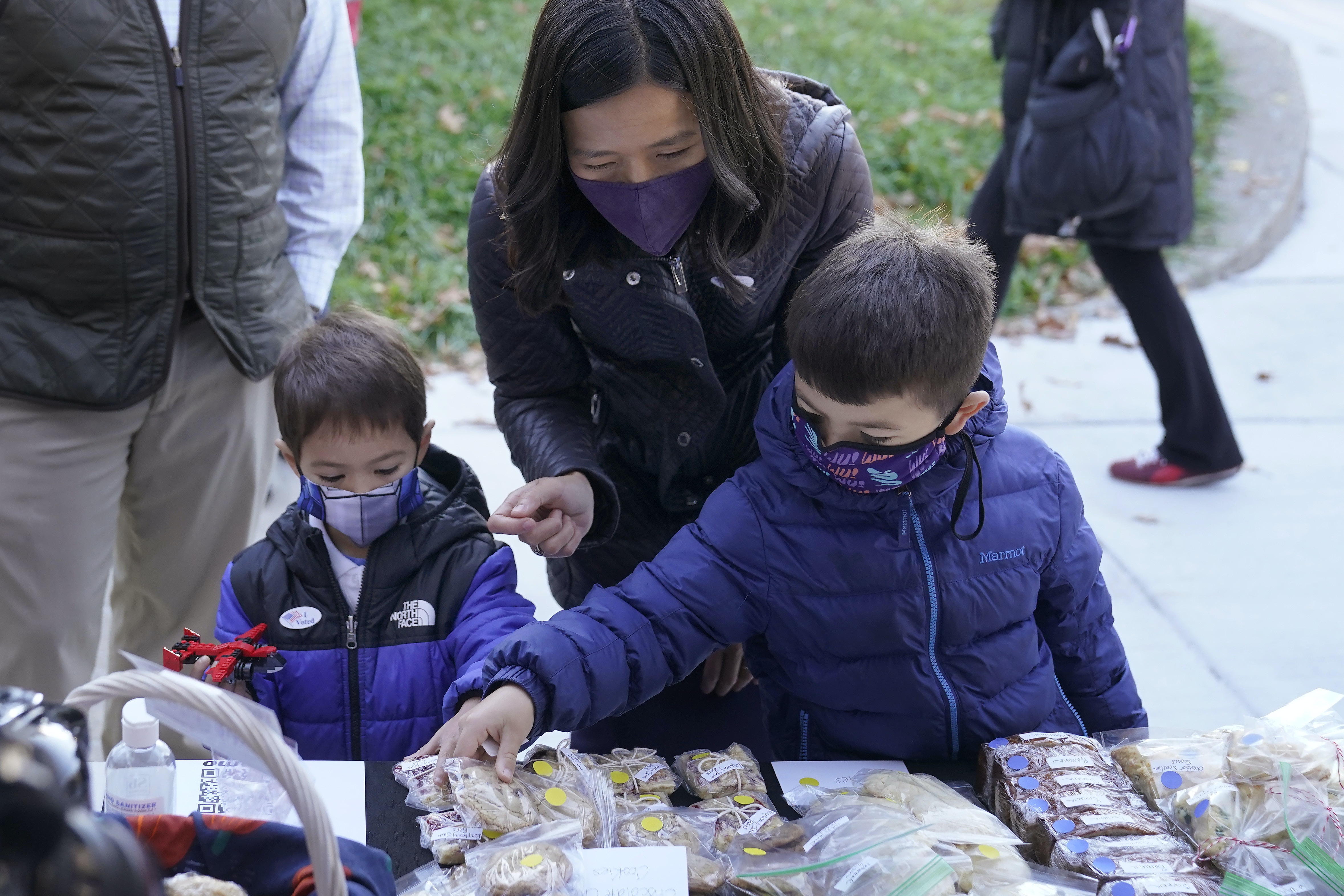 2021年11月2日,星期二,波士頓市長候選人吳弭(中)在波士頓的羅斯林代爾社區投完選票後,和她的兒子卡斯(左)和布萊斯(右)在投票站外參觀糕餅義賣。波士頓選民星期二前往投票站,在民主黨人吳淑珍和安妮薩·埃塞比·喬治中選出市長。(AP) 2021年11月2日,星期二,波士頓市長候選人吳弭(中)在波士頓的羅斯林代爾社區投完選票後,和她的兒子卡斯(左)和布萊斯(右)在投票站外參觀糕餅義賣。波士頓選民星期二前往投票站,在民主黨人吳淑珍和安妮薩·埃塞比·喬治中選出市長。(AP)