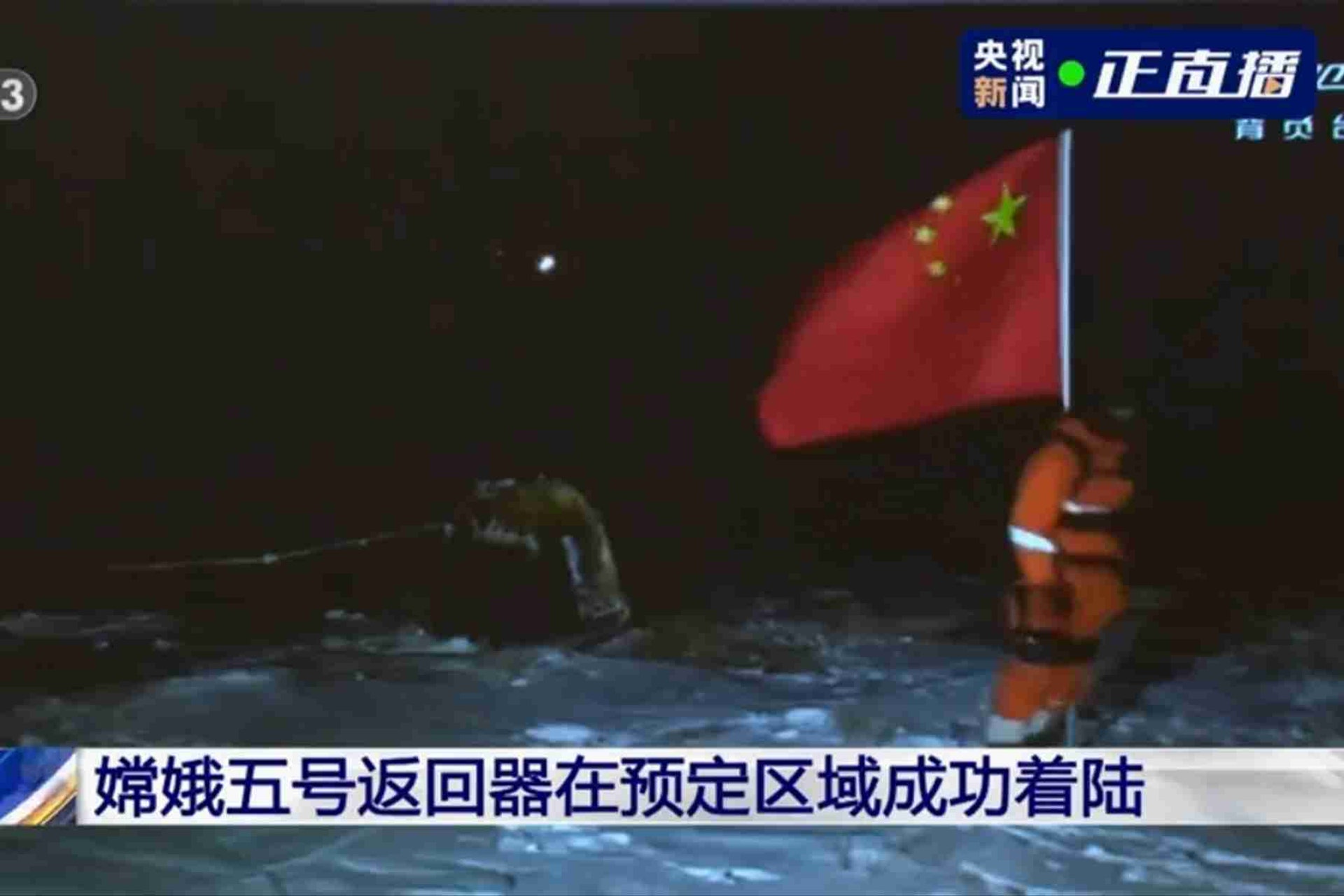 嫦娥五號返回器在預定區域着陸,現場工作人員手舉五星紅旗。(央視截圖) 嫦娥五號返回器在預定區域着陸,現場工作人員手舉五星紅旗。(央視截圖)